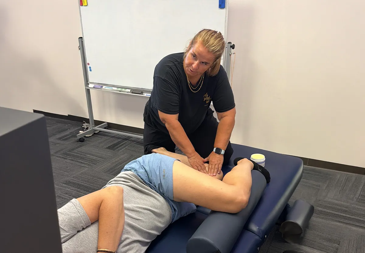 Yodi Richeson working hands-on on a client's hamstring as they lie on their side on a treatment table.